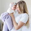 A mother holds her little girl in a buttery-soft Saranoni blanket, featuring a breathable, plush waffle texture in a soothing light purple hue. This luxury toddler blanket is the best kids blanket as a baby blanket or toddler blanket—perfect as a cozy blanket for snuggles or a must-have infant blanket. Designed for softness and comfort, this plush toddler blanket makes an ideal toddler gift. Enjoy this luxury blanket!