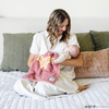 A mother holds her baby girl in a pink and yellow double-layer Bamboni® blanket with a Wonder Woman™ icon on it. The soft blanket is a luxury blanket and a mini blanket as well as a Saranoni blanket. This kids blanket is perfect for littles. 