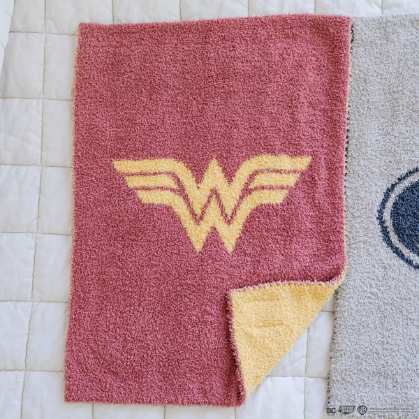 A pink and yellow double-layer Bamboni® blanket with a Wonder Woman™ icon on it. The soft blanket is a luxury blanket and a mini blanket as well as a Saranoni blanket. This kids blanket is perfect for littles. 