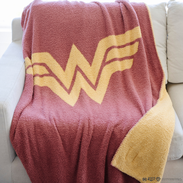 A pink and yellow double-layer Bamboni® blanket with a Wonder Woman™ icon on it. The soft blanket is a luxury blanket and a throw blanket as well as a Saranoni blanket. 