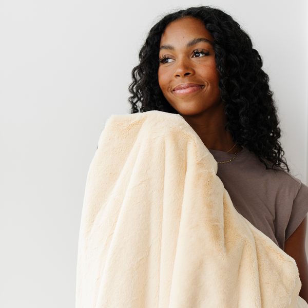 A woman holds a Luxury Extra Large Oversized Throw Chiffon (light yellow) Colored Lush Saranoni Blanket. The soft blanket is an extra large throw blanket and has a soft faux fur feeling.