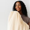 A woman holds a Chiffon (light yellow) Lush XL Saranoni blanket, designed for oversized comfort and featuring a buttery soft, plush texture. This luxurious Saranoni blanket is perfect for cozy evenings, reading, or home decor. The Saranoni blanket adds warmth, style, and unmatched softness, making it an ideal gift or essential for ultimate relaxation.