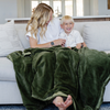 A mother holds her little boy while sitting under a Luxury Extra Large Oversized Throw Fern Colored Lush Saranoni Blanket. The soft blanket is an extra large throw blanket and has a soft faux fur feeling.