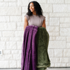 A woman holds a Luxury Extra Large Oversized Throw Aubergine (deep purple) Colored Lush Saranoni Blanket and a Luxury Extra Large Oversized Throw Fern Colored Lush Saranoni Blanket. The soft blanket is an extra large throw blanket and has a soft faux fur feeling.