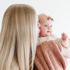 A mother holds her little girl in a French Rose colored Bamboni® Saranoni Blanket. The soft blanket is a small blanket and a baby blanket as well as a mini blanket.