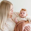 A mother holds her little girl in a French Rose colored Bamboni® Saranoni Blanket. The soft blanket is a small blanket and a baby blanket as well as a mini blanket.