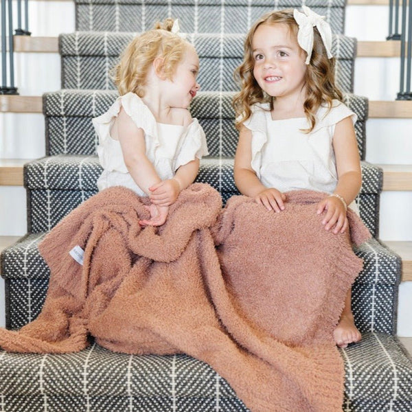 Two girls playing on the stairs, wrapped in French Rose BAMBONI® RECEIVING BLANKETS - Saranoni