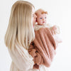 A mother holds her little girl in a French Rose colored Bamboni® Saranoni Blanket. The soft blanket is a small blanket and a baby blanket as well as a receiving blanket.