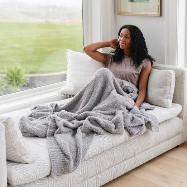 Girl laying by window with her favorite, softest, stretchiest Gray BAMBONI® THROW BLANKETS - Saranoni