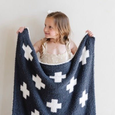 Little girl holding out her favorite Charcoal Swiss Cross DOUBLE-LAYER BAMBONI® MINI BLANKETS - Saranoni