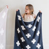 Little girl holding up beautiful, stretchy-soft Charcoal Swiss Cross DOUBLE-LAYER BAMBONI® RECEIVING BLANKETS - Saranoni