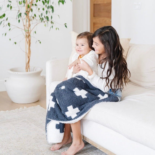 Little girl and baby sister snuggling on couch with Charcoal Swiss Cross DOUBLE-LAYER BAMBONI® RECEIVING BLANKETS - Saranoni