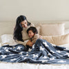 Mom and son smiling and snuggling together in bed with Charcoal Swiss Cross DOUBLE-LAYER BAMBONI® XL BLANKETS - Saranoni