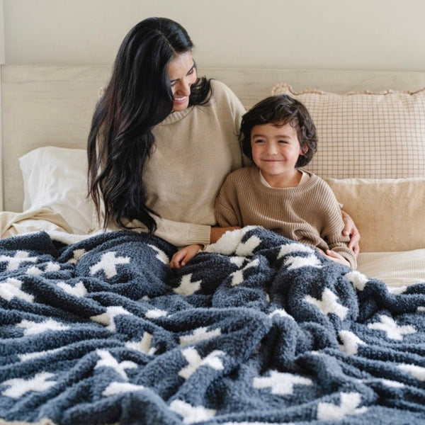 Mom and little boy snuggling together in bed with stretchy soft Charcoal Swiss Cross DOUBLE-LAYER BAMBONI® XL BLANKETS - Saranoni