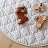 Toys on a soft moonbeam colored minky play mat in a circle shape, 36 inches in diameter, with durable quilting. Ideal as a portable and quilted baby play mat for on-the-go comfort and easy packing in a diaper bag.