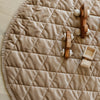 Toys on a soft hazelnut colored minky play mat in a circle shape, 36 inches in diameter, with durable quilting. Ideal as a portable and quilted baby play mat for on-the-go comfort and easy packing in a diaper bag.