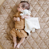 A little boy lays on a soft hazelnut colored minky play mat in a circle shape, 36 inches in diameter, with durable quilting. Ideal as a portable and quilted baby play mat for on-the-go comfort and easy packing in a diaper bag.