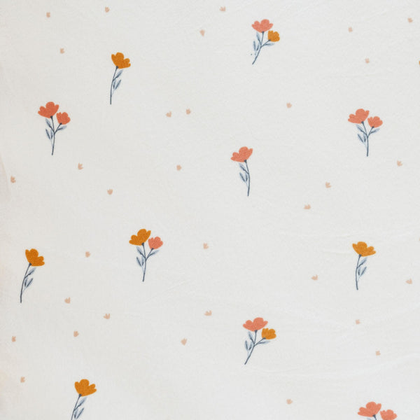 Close-up of Minky Stretch Luxe fabric in a delicate floral pattern, featuring soft peach and orange flowers on a cream background. Made from 94% polyester and 6% spandex, this ultra-soft, stretchy fabric is perfect for baby essentials like swaddles, changing pad covers, and crib sheets.