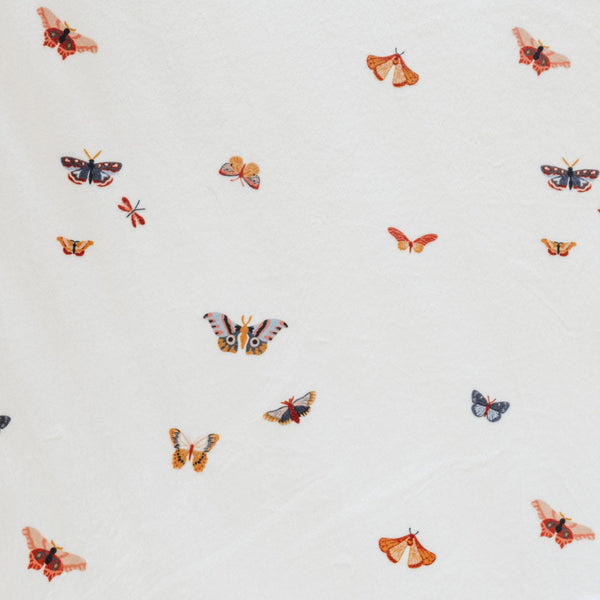 Close-up of Minky Stretch Luxe fabric in a delicate butterfly pattern. Made from 94% polyester and 6% spandex, this ultra-soft, stretchy fabric is perfect for baby essentials like swaddles, changing pad covers, and crib sheets.