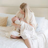 A mother holds her baby girl in a Minky Stretch Luxe swaddle in gingham pattern, featuring ultra-soft minky fabric with a luxurious stretch, perfect for keeping your baby cozy and comfortable. Ideal for newborns and infants.