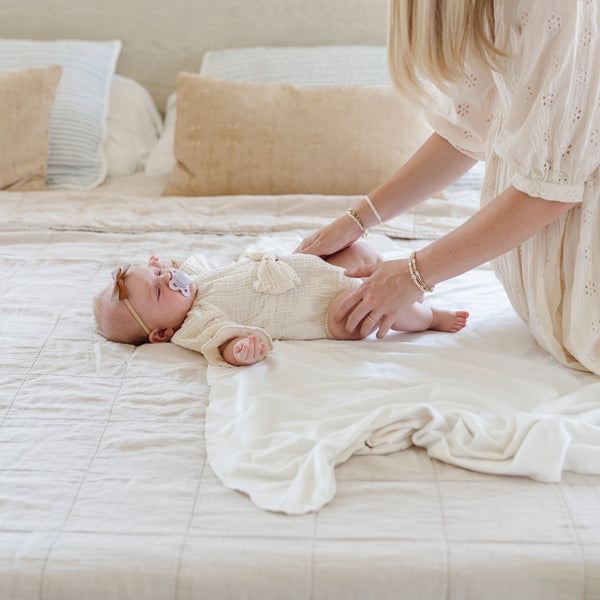 A mother wraps her baby girl in a Minky Stretch Luxe swaddle, featuring ultra-soft minky fabric with a luxurious stretch, perfect for keeping your baby cozy and comfortable. Ideal for newborns and infants.