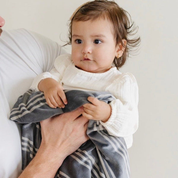 Baby holding on to blue and white striped MINKY STRETCH RECEIVING BLANKETS - Saranoni