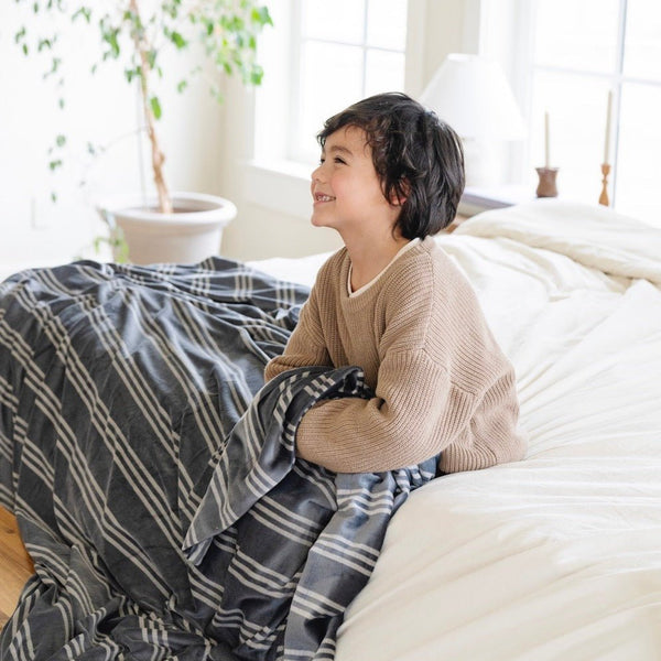 Boy snuggling with blue and white striped MINKY STRETCH THROW BLANKETS - Saranoni