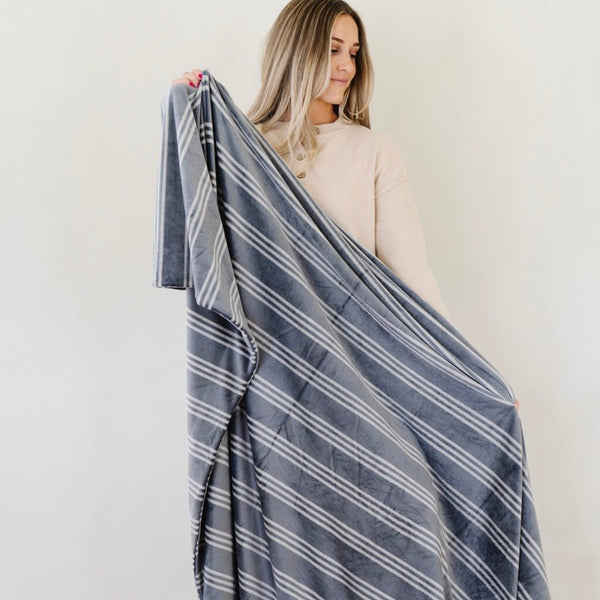 Woman holding up striped blue and white MINKY STRETCH XL THROW BLANKETS - Saranoni