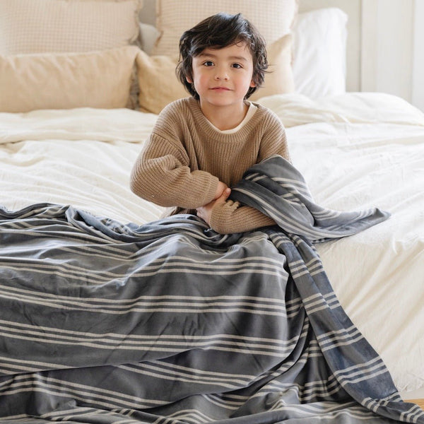 Young boy snuggling with blue and white MINKY STRETCH XL THROW BLANKETS - Saranoni