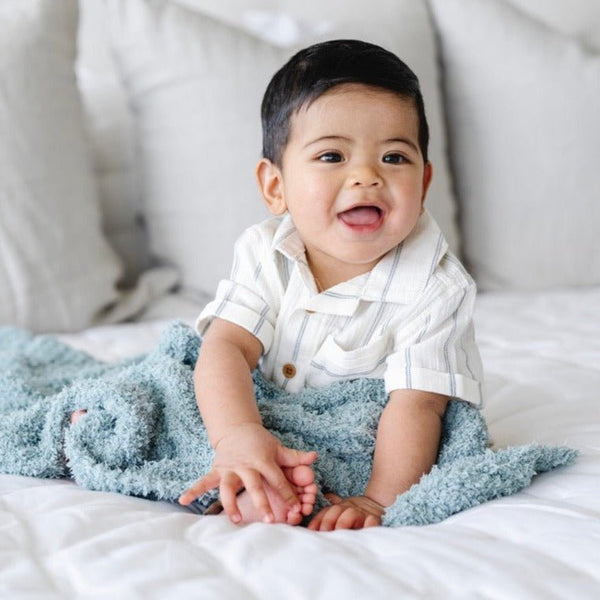 Adorable baby boy playing on bed with extra soft Blue Surf RIBBED BAMBONI® MINI BLANKETS - Saranoni