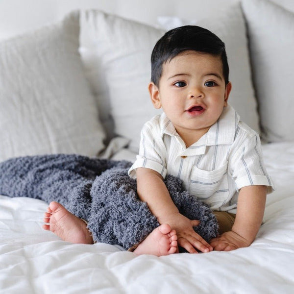 Adorable baby playing on bed with his favorite super soft and warm Charcoal RIBBED BAMBONI® RECEIVING BLANKETS - Saranoni