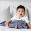 Little boy playing on bed with super soft and cozy Charcoal RIBBED BAMBONI® RECEIVING BLANKETS - Saranoni