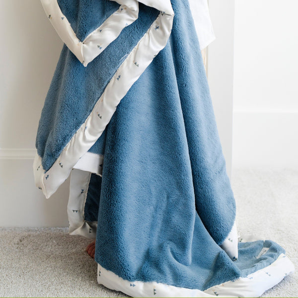 Warm and comforting blue and white toddler blanket featuring a soft, velvety surface on one side and a satin back, offering the ideal combination of coziness and elegance.