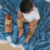 Little boy enjoying playtime on a cozy and silky blue and white satin back toddler blanket. 