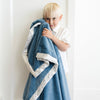 Young boy snuggled up with a blue toddler blanket featuring a satin back, blending a soft, warm texture on one side with a smooth, luxurious satin finish on the other.