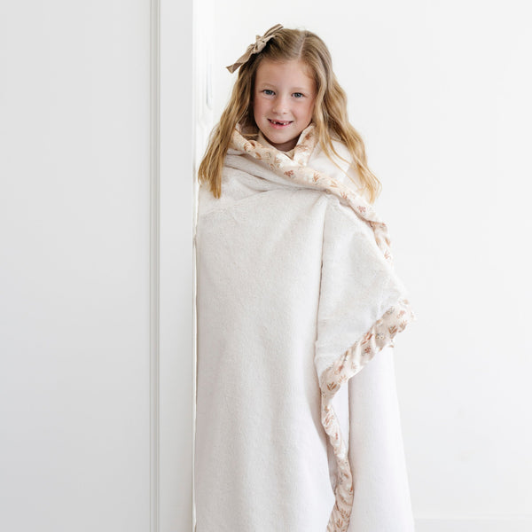 Little girl wrapped in an elegant floral ivory toddler blanket.