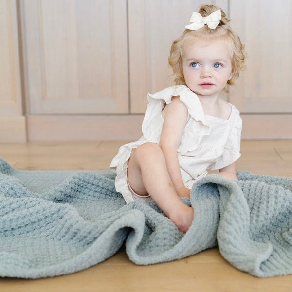 Close-up of little girl cuddling with Elm Waffle Knit Toddler blanket showing its textured pattern