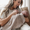 Mom cradling child wrapped in a soothing gray mini satin blanket.