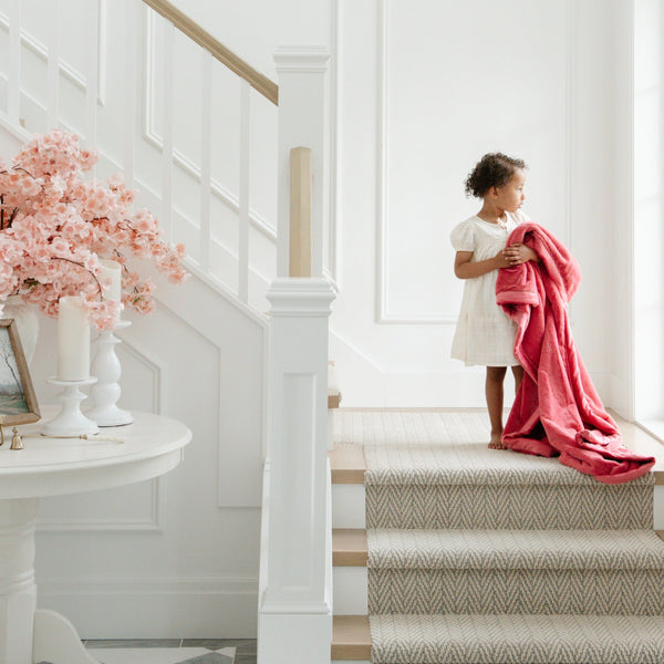 A little girl holds a Toddler Primrose (bold pink) Colored Lush Luxury Saranoni Blanket. The soft blanket is a baby blanket or toddler blanket.