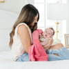 A mother holds her baby girl in a Mini Primrose (bold pink) Colored Lush Saranoni Blanket. The soft blanket is a small blanket and a baby blanket or toddler blanket.