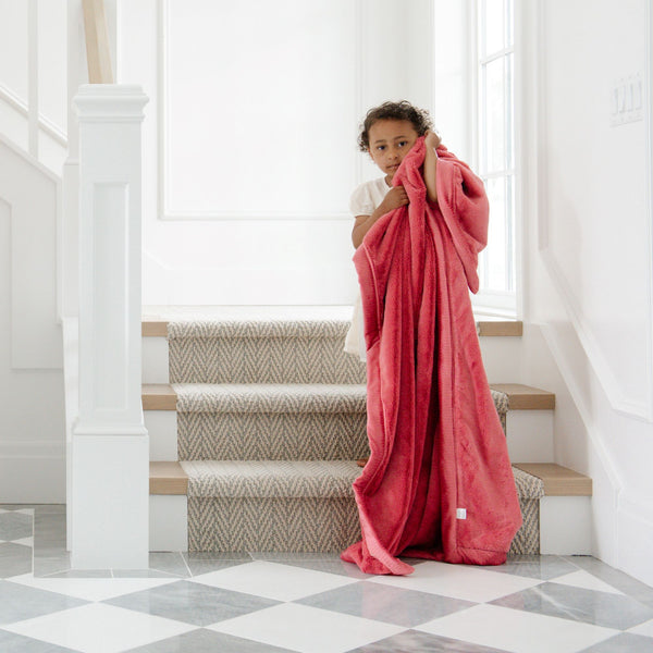 A little girl holds a Luxury Extra Large Oversized Throw Primrose (bold pink) Colored Lush Saranoni Blanket. The soft blanket is an extra large throw blanket and has a soft faux fur feeling.