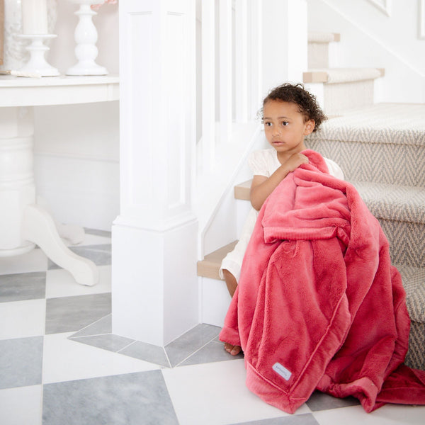 A little girl holds a Luxury Extra Large Oversized Throw Primrose (bold pink) Colored Lush Saranoni Blanket. The soft blanket is an extra large throw blanket and has a soft faux fur feeling.