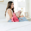 A mother holds her baby girl in a Mini Primrose (bold pink) Colored Lush Saranoni Blanket. The soft blanket is a small blanket and a baby blanket or toddler blanket.