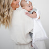 Mom and daughter playing together wrapped in a white receiving blanket.