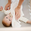 Baby cuddling in crib with a cozy ivory satin border mini blanket.