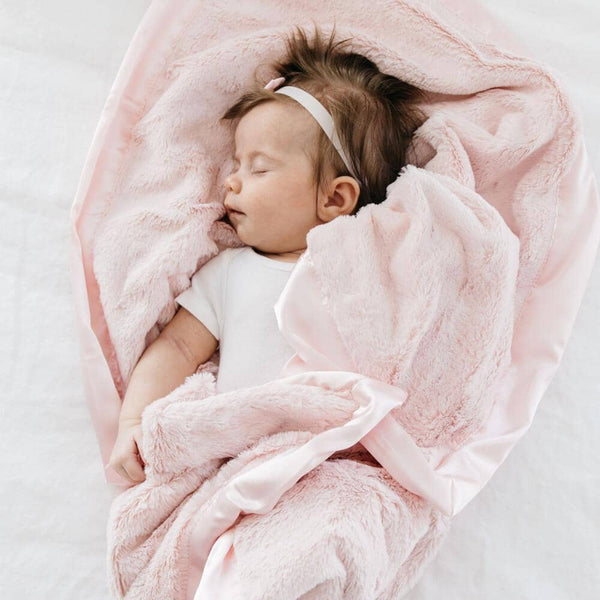 Baby girl wrapped in a cozy light pink receiving blanket.