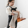 Little girl playing with a mini blanket with a plush, cushioned texture and a satin border, perfect for providing warmth and comfort with a sophisticated finish.