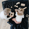 A little boy and a little girl play on a Luxury Toddler Charcoal Colored Lush Saranoni Blanket. The soft blanket is a toddler blanket or baby blanket.