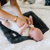 A newborn lays on top of a Charcoal Colored Lush Saranoni Blanket. The soft blanket is a small blanket and a baby blanket.