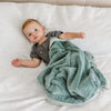 A little boy lays under a Luxury Receiving Eucalyptus Colored Lush Saranoni Blanket. The soft blanket is a small blanket and a baby blanket or toddler blanket.